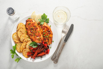 Wall Mural - Marinated grilled chicken breasts cooked and served with potato chips on a stone light gray background.