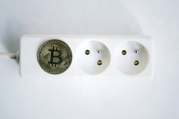 bitcoin coin lying on power strip extension cord with two empty sockets, cryptocurrency investing, e