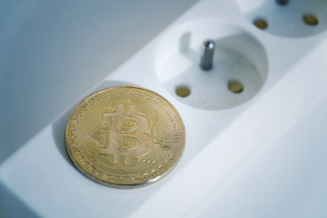 Wall Mural - bitcoin coin lying on power strip extension cord with two empty sockets, cryptocurrency investing, e