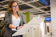 © scharfsinn86 - Woman uses the self-service kiosk in the store