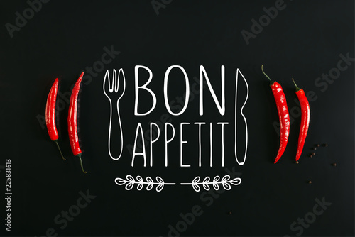Plakaty do jadalni top-view-of-red-chili-peppers-and-peppercorns-on-black-background-with-bon-appetit-lettering-with-fork-and-knife