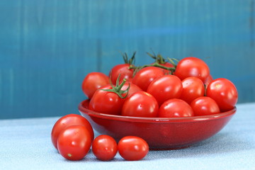 red tomatoes in a bowl on blue background.