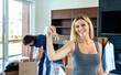 Young woman showing the keys of her new house while her husband unpacks boxes