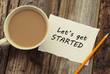 Let's get started inscription on white blank papper. Cup of coffee and pencil, over rustic wooden background.