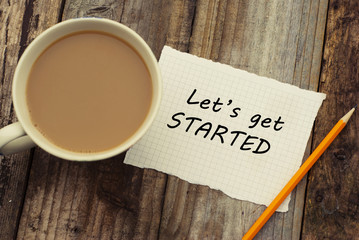 let's get started inscription on white blank papper. cup of coffee and pencil, over rustic wooden ba