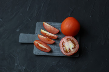 Two tomatoes on a gray ceramic rain Tasty food for your recipes on a dark background.