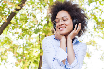 Wall Mural - Beautiful Happy Afro American Young Woman Listening Music In Nature