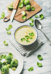 Wall Mural - Seasonal brussels sprouts vegetable cream soup in bowl and fresh green brussel sprouts over grey marble background, selective focus. Vegan, vegetarian, healthy, dieting food concept