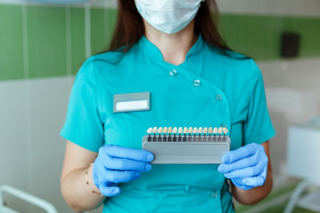 dentist holding in hands matching the shades or color of the implants or the process of teeth whitening.