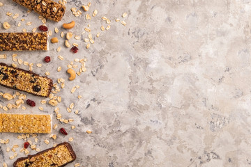 Wall Mural - Mixed gluten free granola cereal energy bar with dried fruit & various nuts, gray concrete background. Healthy vegan super food, fitness dieting snack for sporty lifestyle. Top view, copy space.