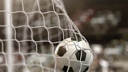 Beautiful soccer ball flies into the net of the gate in the stadium filled with spectators. The movement at the beginning is accelerated then slowly
