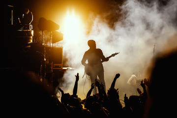 silhouette of guitar player, guitarist perform on concert stage. dark background, smoke, concert spo