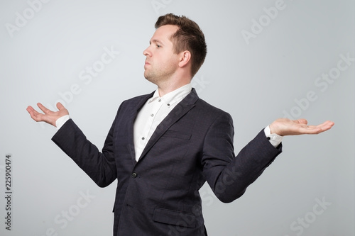 Foto Self-satisfied and proud caucasian young man looks aside and spread his hands