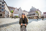 Portrait of a young woman tourist standing on the beautiful city square with old buildings, traveling in Nurnberg, Germany