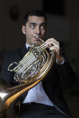 French horn player. Hornist playing brass orchestra music instrument.