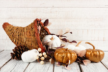 Thanksgiving Cornucopia Filled With White And Gold Pumpkins Against A White Wood Background