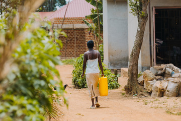 Wall Mural - woman carrying water in Uganda, Africa