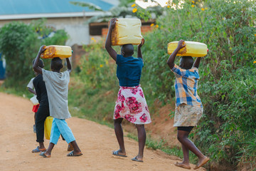 Children carrying water cans in Uganda, Africa