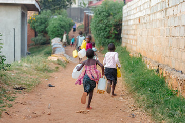 children carrying water cans in uganda, africa