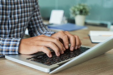 hands of programmer coding on laptop at his table