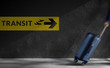 Traveling Concept. Blurred Traveler Walking with Luggage in a Hurry inside the Airport, Transit Sign on the Wall as background