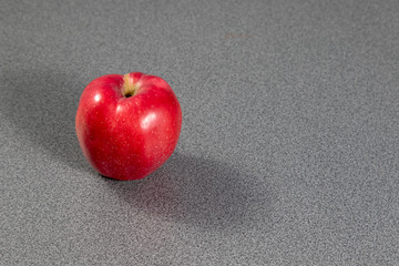 Single red apple lying on grey table