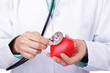 © jivimages - Health concept: Unrecognizable doctor holding a stethoscope on a red heart