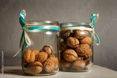 Two Glass Jars Filled With Whole Walnuts Decorated With Ribbons