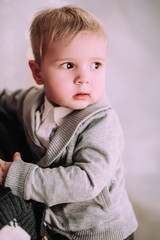 Cheerful little baby boy playing near Christmas tree, gold and beige pastel c