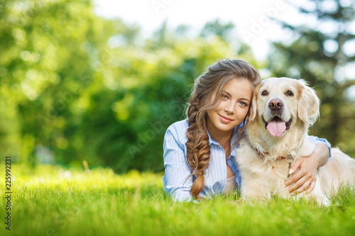 Cuadros en Lienzo Young woman with golden retriever dog in the summer park