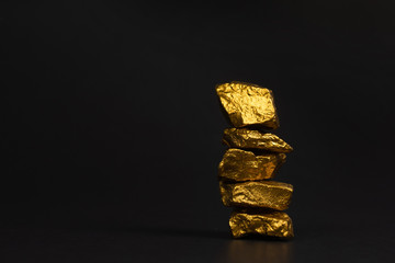 A pile of gold nuggets or gold ore on black background, precious stone or lump of golden stone, financial and business concept.