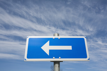 traffic sign arrow pointing left against sky