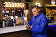 © Alyona - man looks into the phone behind the bar