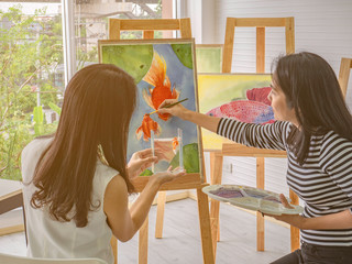 Two young asian woman artist dawning while useing ideas to think and create the best artwork together,fish concept