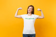 © ViDi Studio - Portrait of happy smiling satisfied woman in white t-shirt with written inscription green title volunteer isolated on yellow background. Voluntary free assistance help, charity grace work concept.