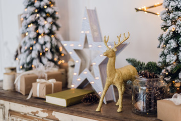 winter still life with Christmas decorations toy deer, star and gift boxes on light background. soft focus, blurred background