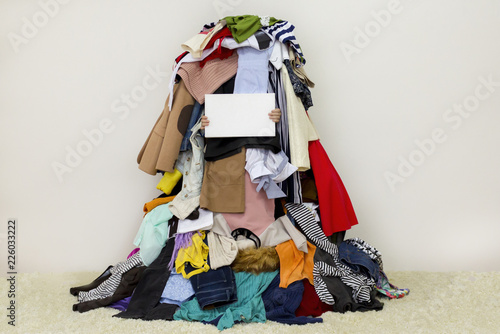 Fotografía Hands holding empty board shown from a big pile of clothes