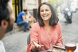 © Lomb - Adult woman laughing and talking with a group of friend in a outdoor bar. Mid aged adult frienship and fun concept, mid season clothes.
