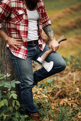 bearded man with red shirt and axe posing near tree