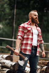 Wall Mural - bearded mohawk lumberjack worker standing in forest with axe