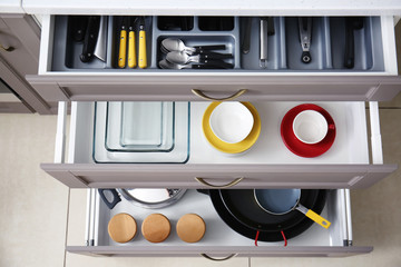 Set of clean kitchenware and utensils in drawers