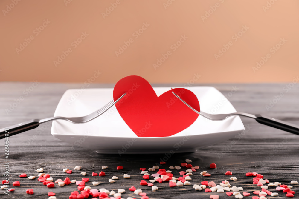 Color heart between two forks on wooden table