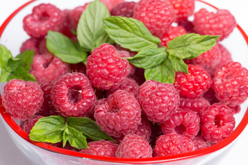 Sweet Raspberry with raspberry with mint leaves in a glass plate on white background.