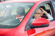 Annoyed mature woman sitting in a car, stuck in a traffic jam. Front side view through side window. Commuting by car concept.