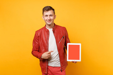 Portrait vogue fun young man in red leather jacket, t-shirt hold tablet pc pad with blank empty screen isolated on bright yellow background. People sincere emotions lifestyle concept. Advertising area