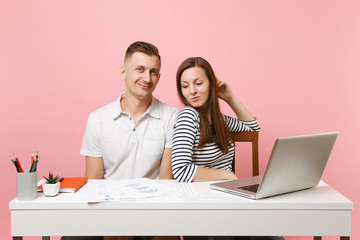 Two young tender business woman man colleagues sit work at white desk with contemporary laptop isolated on pastel pink background. Achievement career concept. Copy space advertising, youth co working.