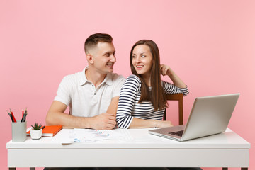 Two young tender business woman man colleagues sit work at white desk with contemporary laptop isolated on pastel pink background. Achievement career concept. Copy space advertising, youth co working.