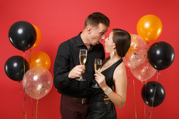 Stunning young couple in black clothes celebrating birthday holiday party isolated on bright red background air balloons. St. Valentine's International Women's Day Happy New Year 2019 concept. Mock up