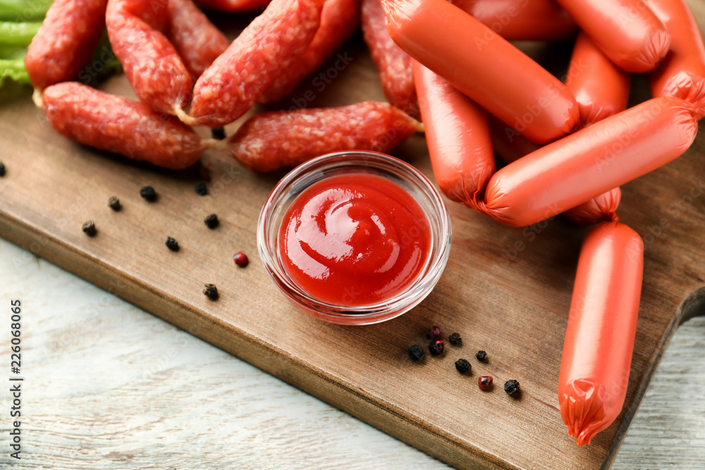 Delicious sausages with sauce on wooden board
