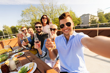 Wall Mural - leisure and people concept - happy friends having bbq party on rooftop in summer and taking selfie